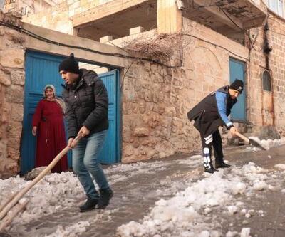 Polisler ve öğrenciler, yaşlı kadının evinin önündeki karı temizledi